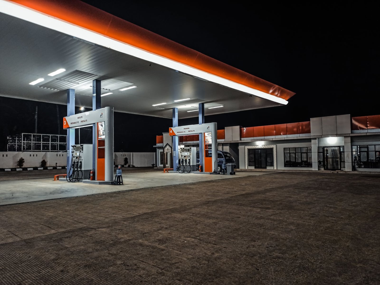 Una estación de gasolina contemporánea iluminada por la noche, destacando las estaciones de bombeo y el toldo.