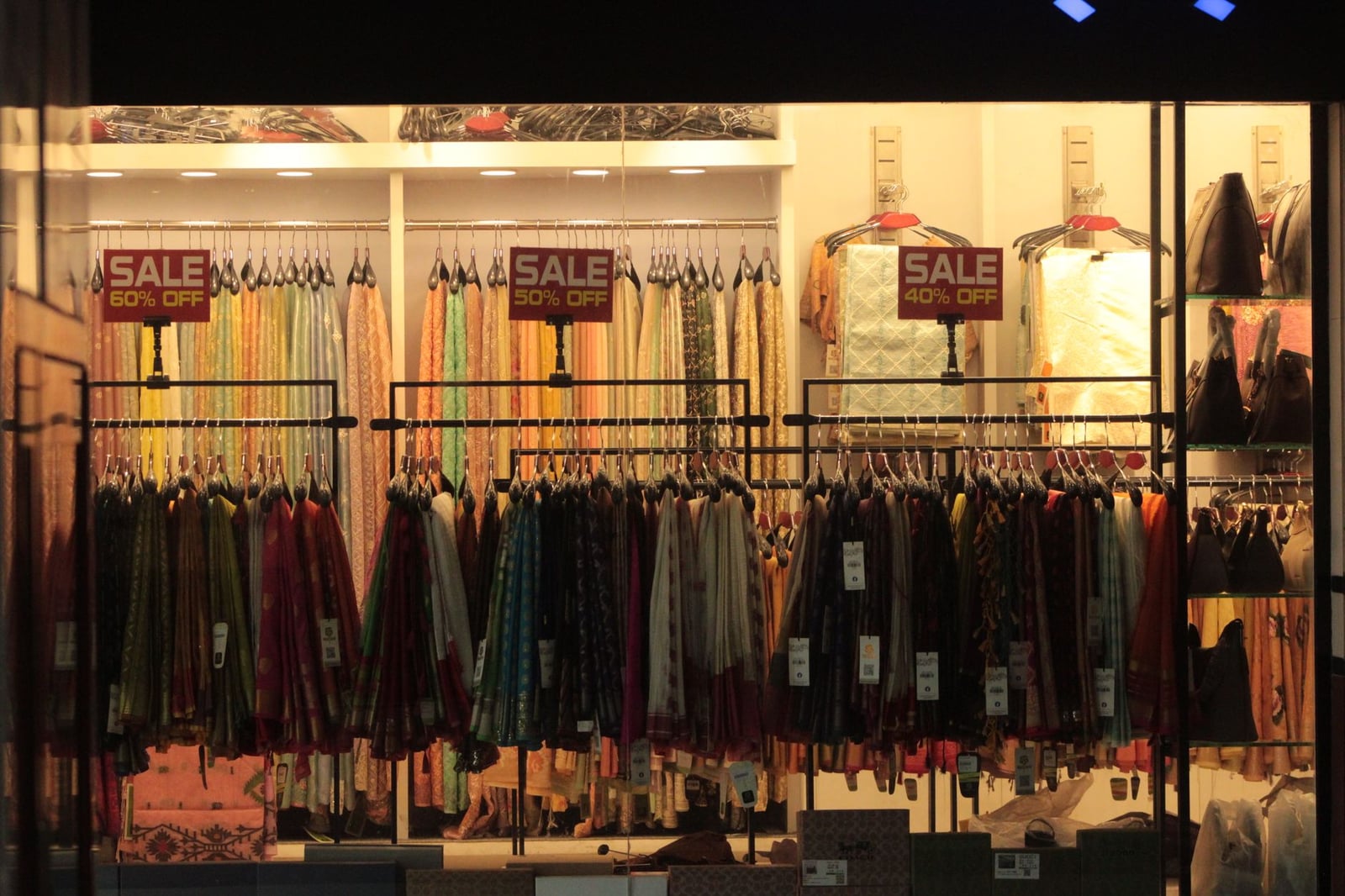 Interior de tienda de ropa vibrante que exhibe telas coloridas con carteles de descuento.