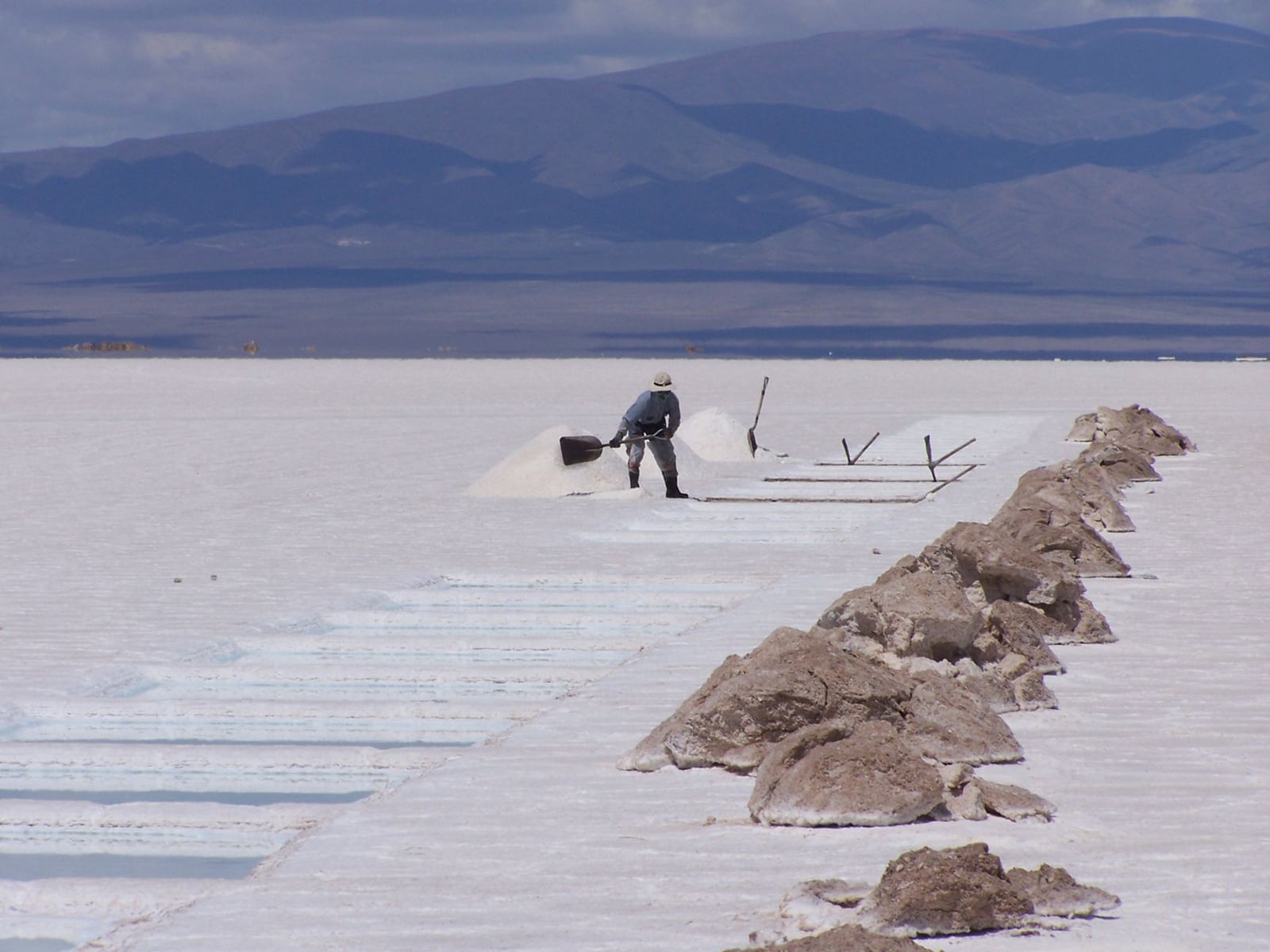 Un trabajador en Salta, Argentina, cavando sal en extensas salinas bajo un cielo despejado.