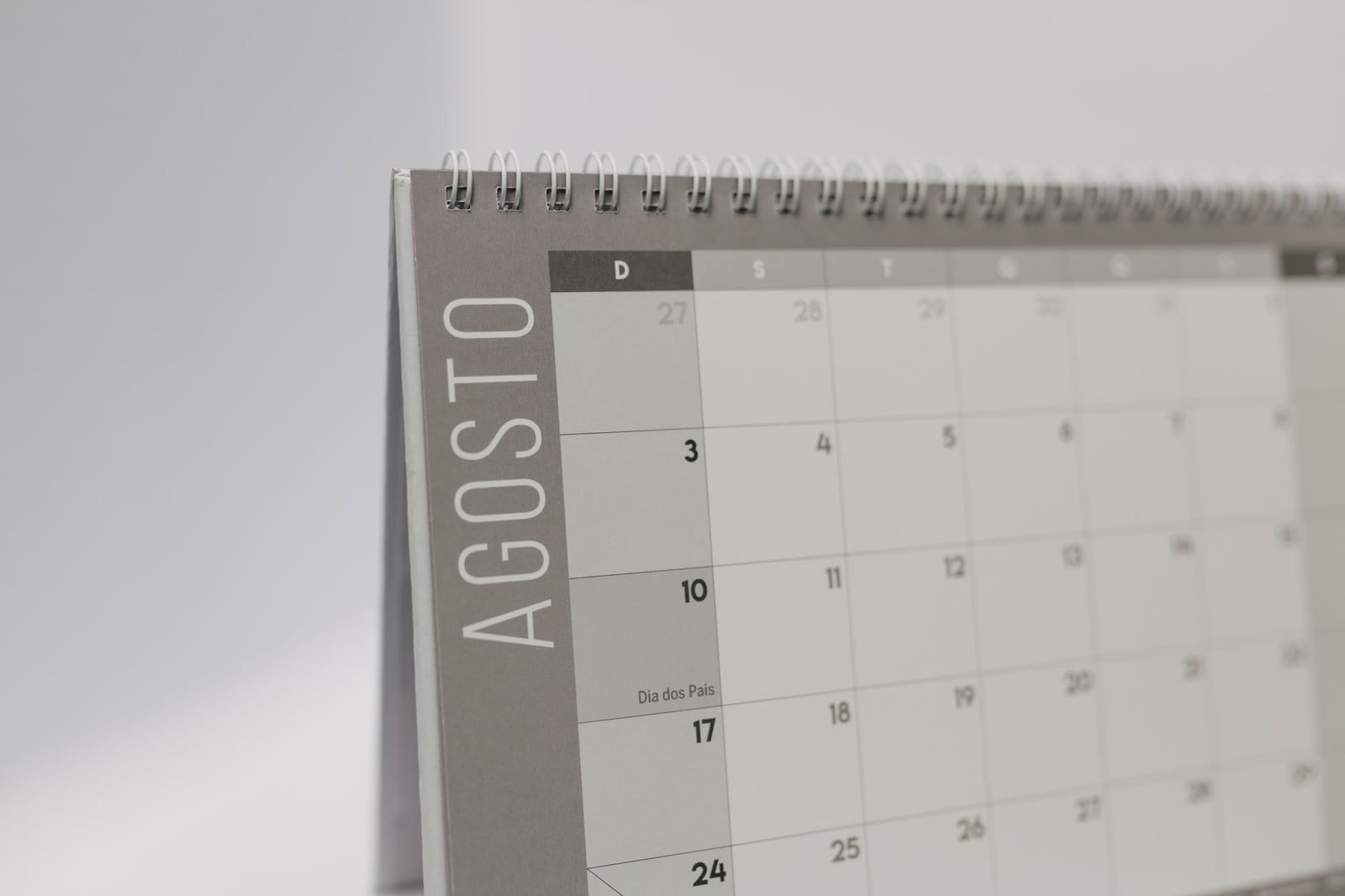 Primer plano de un calendario de escritorio que muestra agosto en portugués con un diseño minimalista.