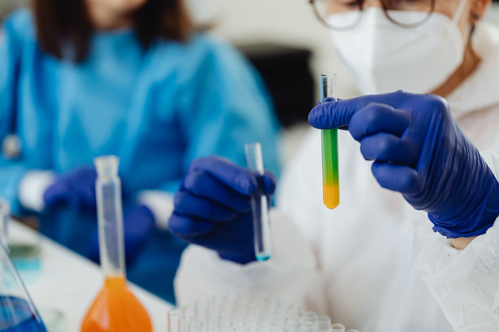 Acercamiento de científicos trabajando con tubos de ensayo coloridos en un entorno de laboratorio.