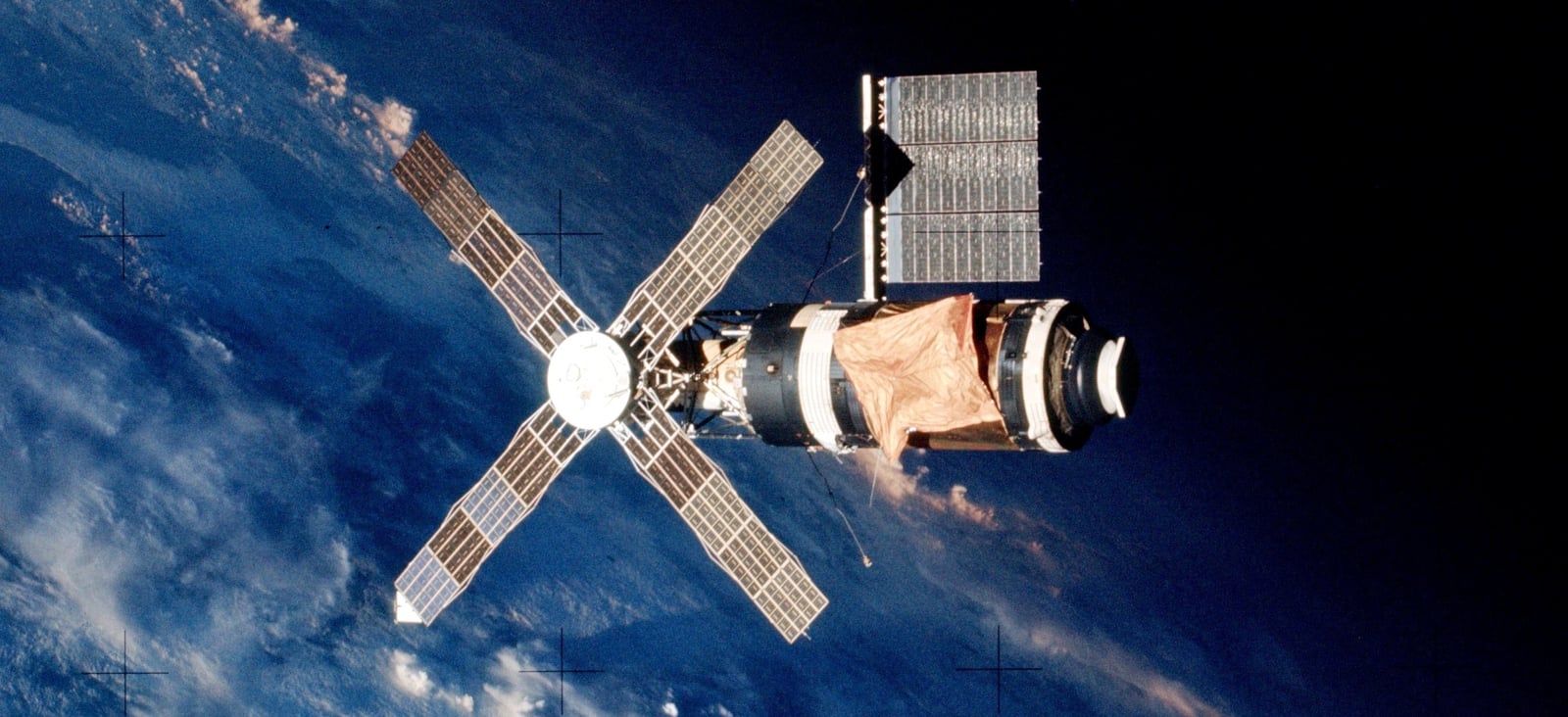 As the crew of Skylab 2 departs, the gold sun shield covers the main portion of the space station. The solar array at the top was the one freed during a spacewalk. The four, windmill-like solar arrays