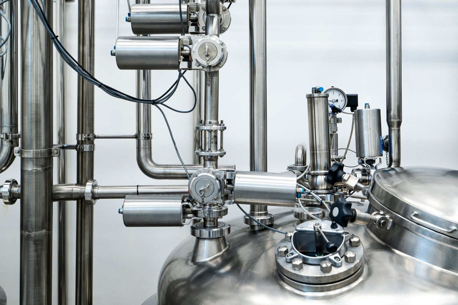 Primer plano de maquinaria y tuberías de acero inoxidable en un entorno industrial, que muestra la ingeniería moderna.