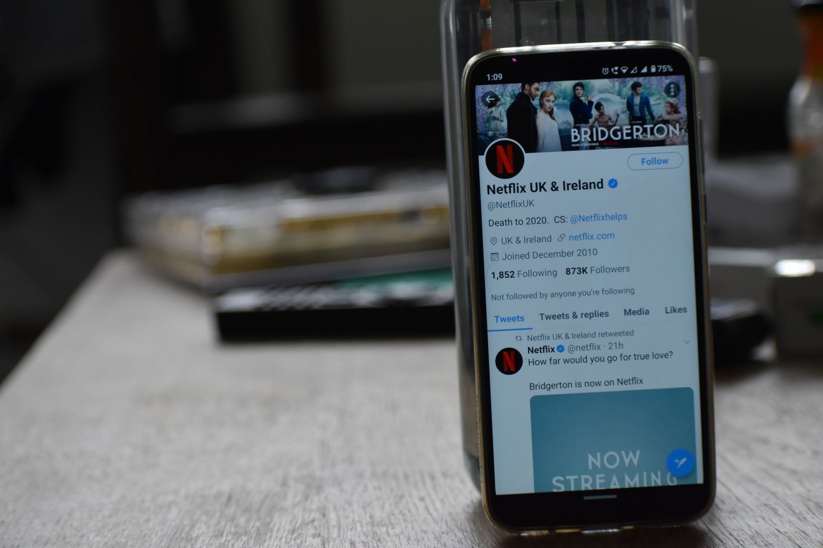 Teléfono inteligente mostrando la página de Twitter de Netflix sobre una mesa de madera.