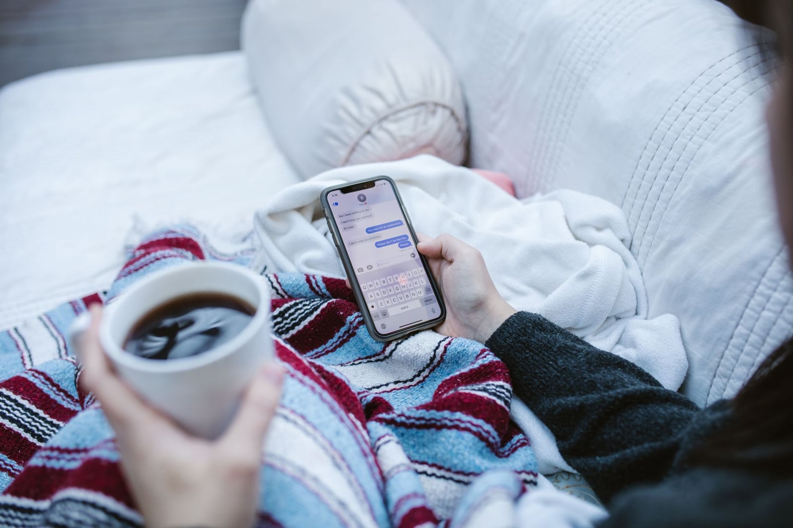 Una Persona Sostiene Una Taza De Café Mientras Usa Un Teléfono Inteligente
