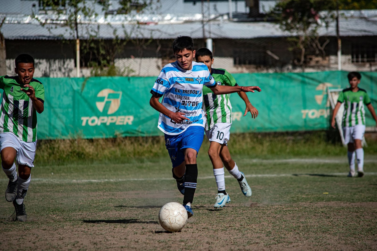 Jóvenes futbolistas en un partido competitivo en un día soleado al aire libre.